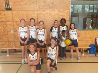 Spielbericht Wu12/2  Ich bin richtig stolz auf die erste Halbzeit! Die Kinder haben super aufmerksam gespielt, in der Verteidigung gut aufgepasst und sich gegenseitig geholfen. Dadurch haben wir dem Gegner kaum einfache Körbe erlaubt. Besonders schön waren unsere schnellen Fastbreaks nach vorne, bei denen wir oft den Ball erobert und direkt Punkte gemacht haben. Außerdem haben sich viele mutig getraut, den Weg zum Korb zu suchen – auch wenn es manchmal eng wurde. Man hat gemerkt, dass wir von Anfang an wach waren und unbedingt zeigen wollten, was wir können.  In der zweiten Halbzeit wurde es dann schwieriger. Wir haben ein bisschen die Körperspannung verloren und dadurch nicht mehr so konsequent gespielt wie noch im ersten Durchgang. Viele Würfe sind nicht mehr gefallen, weil wir sie nicht mehr mit voller Konzentration und Spannung abgeschlossen haben. Beim Rebound waren wir öfter einen Schritt zu spät, und so hatten die Gegner viele zweite Chancen. Anstatt unser Spiel durchzuziehen, mussten wir immer häufiger hinterherlaufen, und die anderen konnten ihr Tempo spielen. Dadurch haben sie es geschafft, immer wieder zu einfachen Punkten zu kommen.  Trotzdem haben die Kinder nicht aufgegeben und bis zum Ende weitergekämpft. Auch wenn uns in dieser Phase die nötige Körperspannung und Energie gefehlt haben, um zurückzukommen, bin ich sehr zufrieden mit vielen Aktionen aus der ersten Halbzeit. Wir nehmen daraus mit, dass wir über das ganze Spiel hinweg konzentriert bleiben müssen – dann können wir es jedem Gegner richtig schwer machen.