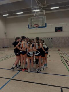 wU14-2 Spielbericht Nachdem wir vor zwei Wochen einen richtig guten Start in die LL hatten, in die wir zur Rückrunde umgemeldet haben, sollte dieses Wochenende unsere erste große Herausforderung werden. Am Samstagabend ging es gegen Alba 3. Wir verloren relativ schnell den defensiven Zugriff und bekamen die Alba-Mädels nicht kontrolliert. Zu viele Ballverluste ermöglichten Alba einfache Fastbreaks, und wir waren im Umschalten immer einen Ticken zu langsam. Offensiv kamen wir zwar immer wieder gut zum Korb, aber es fiel einfach nichts rein, was mental sehr hart war, denn das Offensivspiel wurde nicht belohnt.
Schafften wir es jedoch, Alba ins Set Play zu zwingen, hatten auch sie Probleme. Wir merkten, dass die Physis in dieser Liga eine ganz andere ist: Jeder Rebound muss hart erkämpft werden, und auch mit der körperlichen Defense müssen wir klarkommen. Zur Halbzeit lagen wir mit zehn Punkten zurück, also war noch alles drin. Doch wie gesagt: Es fiel weiterhin nichts, und unsere Kräfte in der Defense ließen zunehmend nach, wodurch Alba uns weglief und wir keine Kontrolle mehr hatten. So mussten wir uns am Ende geschlagen geben. Am Sonntagmorgen ging es dann weiter gegen Alba Gropiusstadt 4. Alba trat nur mit fünf Spielerinnen an, wir waren zwölf. Unser Plan war also klar: viel Tempo machen und viel Druck in der Defense. In den ersten Minuten klappte das auch gut, und wir hatten Alba defensiv gut im Griff und erspielten uns einfache Abschlüsse. Offensiv hatten wir gute Ideen, aber die Defense von Alba stand oft dazwischen, wodurch es schwer war, im Set Play zu scoren.
Doch je länger das Spiel dauerte, desto mehr ließen unsere Kräfte nach, und man merkte uns das Spiel vom Abend davor an. In der Defense liefen wir nicht mehr konsequent zurück, wir schafften es auch nicht mehr, Druck in der Defense zu machen, und dadurch auch keine einfachen Abschlüsse mehr. Auch in diesem Spiel merkten wir erneut die Physis der Liga, an die wir uns erst noch gewöhnen müssen, und dass wir es schaffen müssen, 40 Minuten mithalten zu können. Aber wie gut, dass wir dafür noch die ganze Rückrunde Zeit haben, daran zu arbeiten. Wenn wir schon alles könnten, wäre ja langweilig.